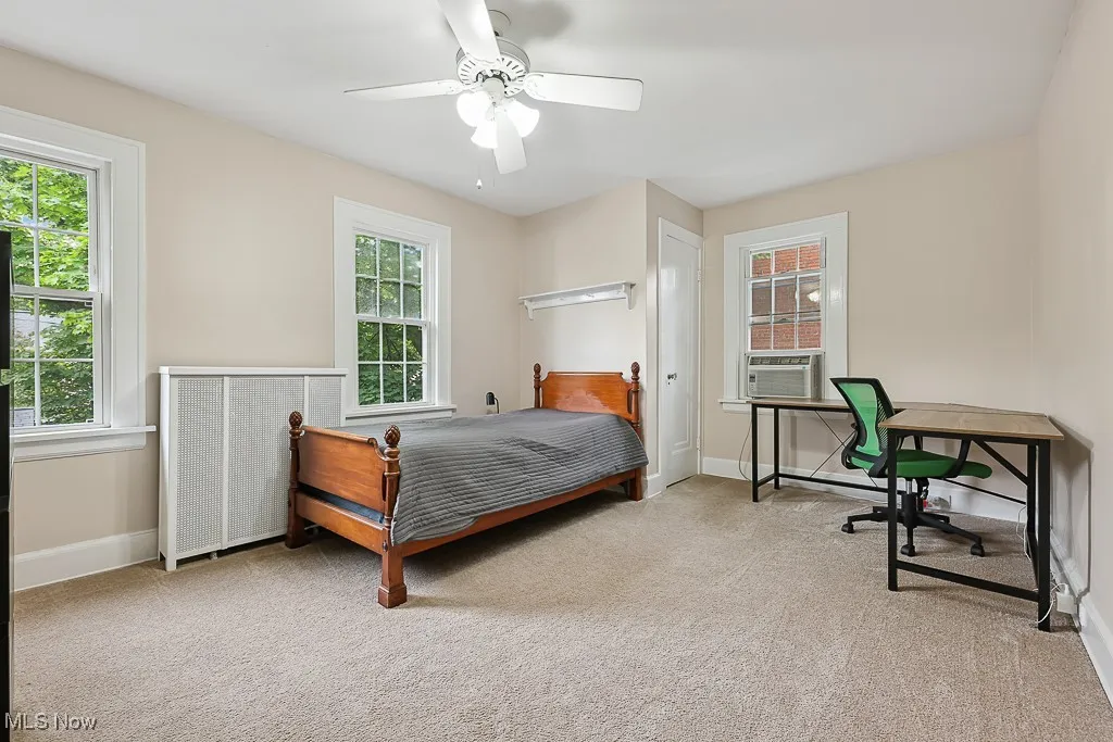 Carpeted bedroom featuring multiple windows and a ceiling fan