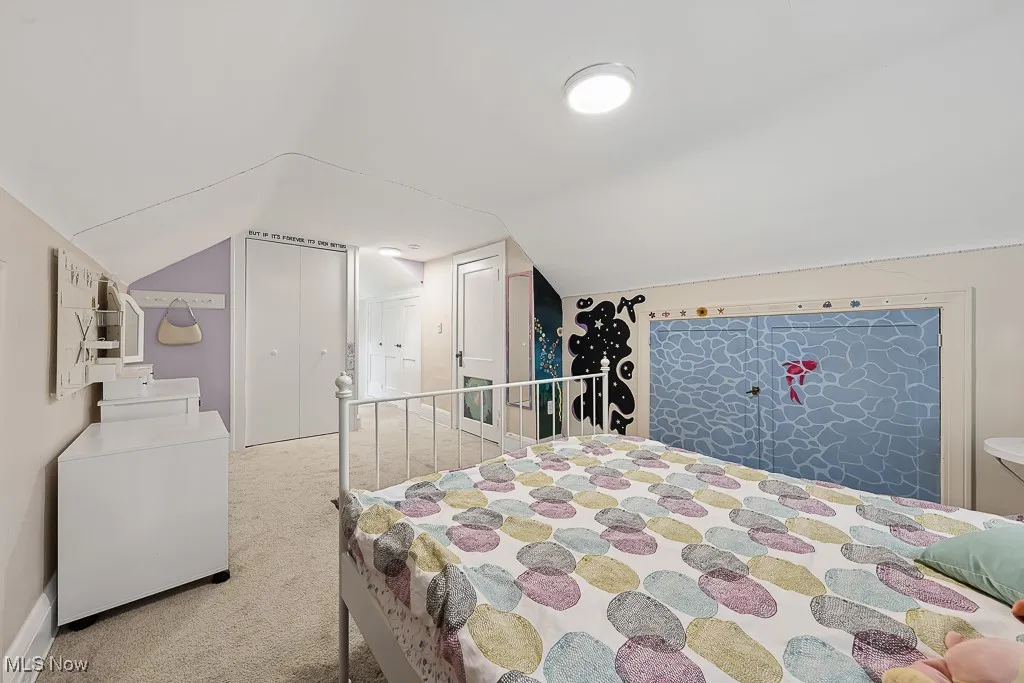 Carpeted bedroom with lofted ceiling and fridge