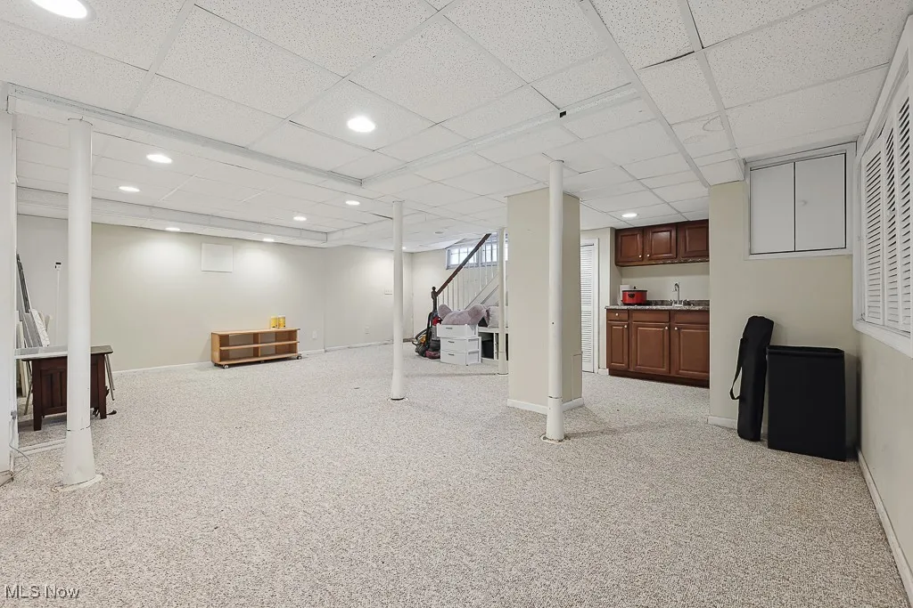 Below grade area featuring a drop ceiling, carpet flooring, recessed lighting, and bar area