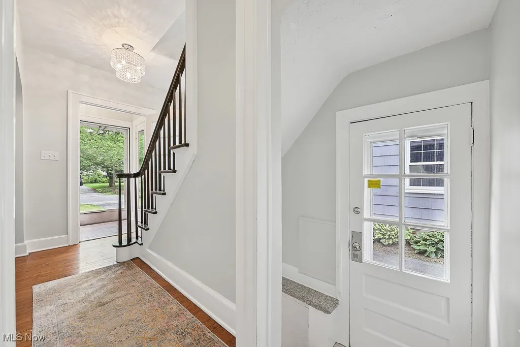 Entryway with wood finished floors, stairway, and a chandelier