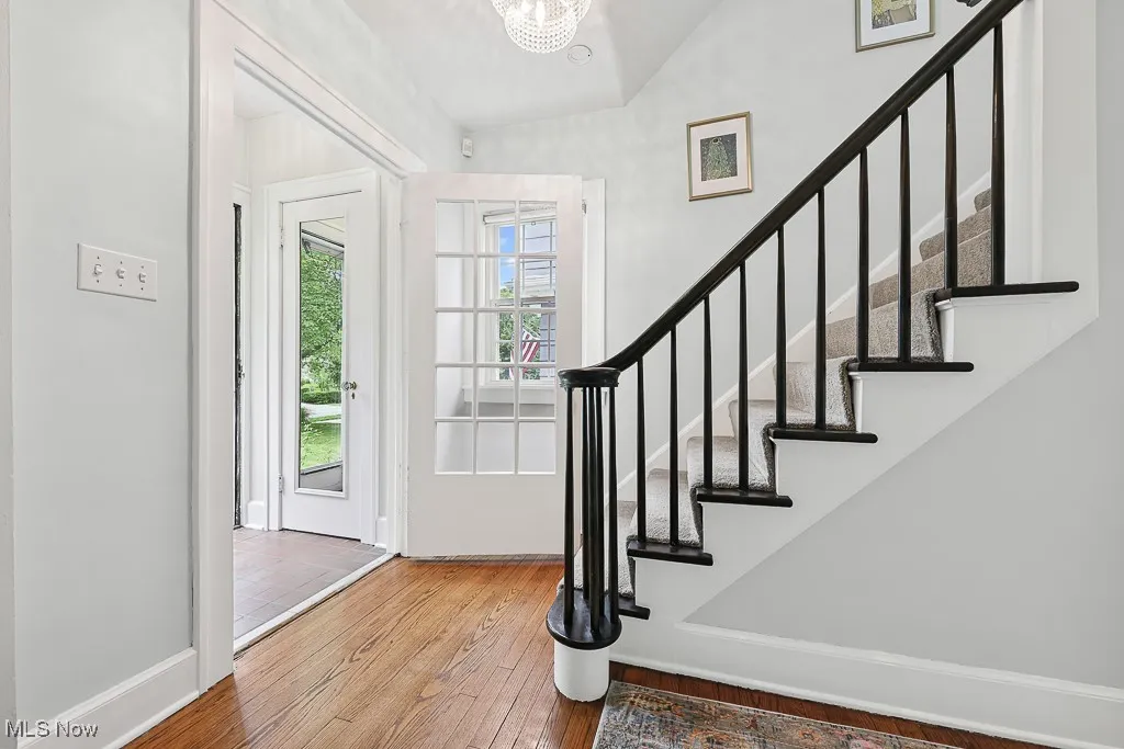 Foyer entrance with hardwood / wood-style flooring, stairs, a chandelier, and vaulted ceiling