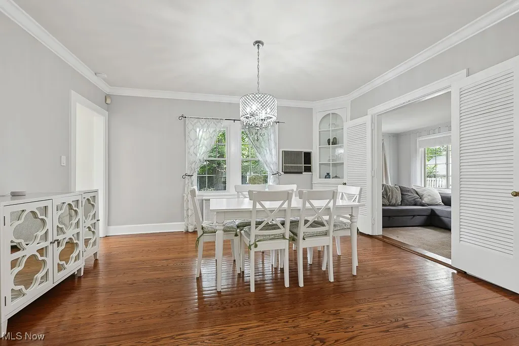 Dining area with ornamental molding, hardwood / wood-style flooring, and a chandelier