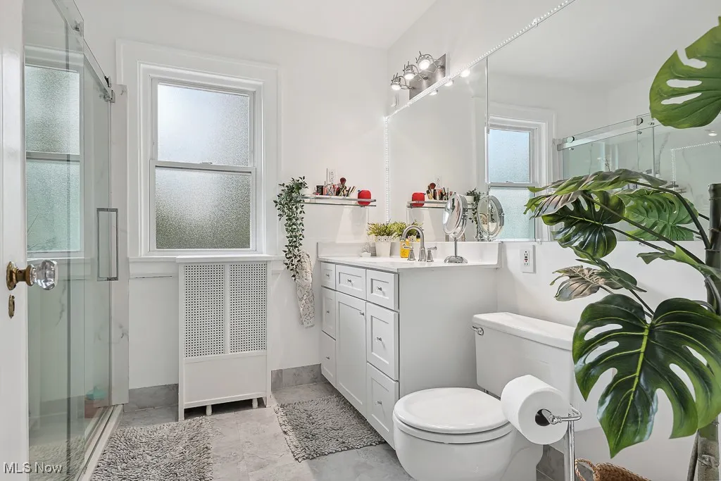Bathroom with vanity, radiator heating unit, and a shower stall