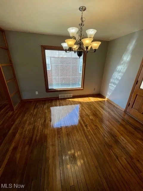 Unfurnished dining area with a chandelier and hardwood / wood-style floors