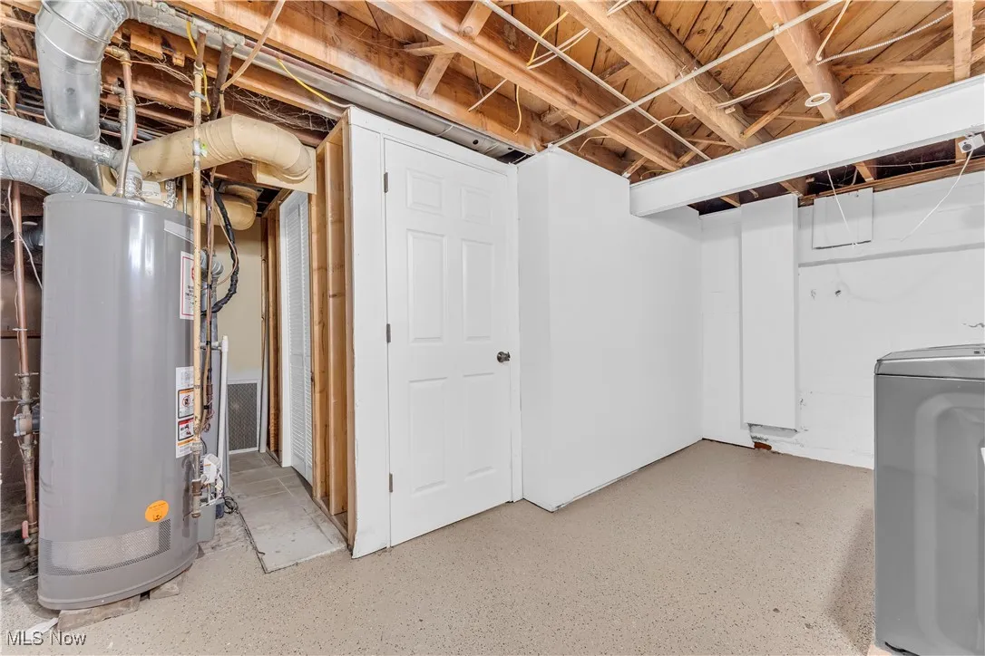 Unfinished basement featuring water heater and washer / clothes dryer
