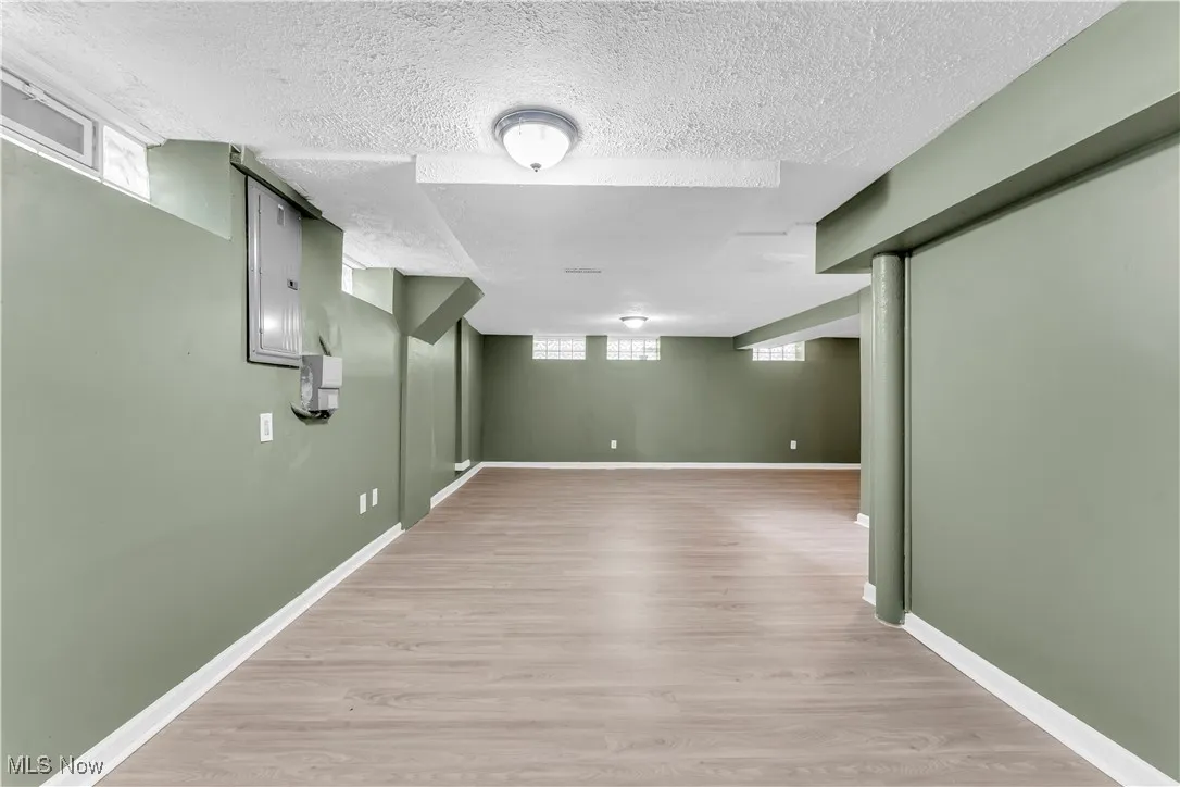Basement with light wood-style floors and a textured ceiling