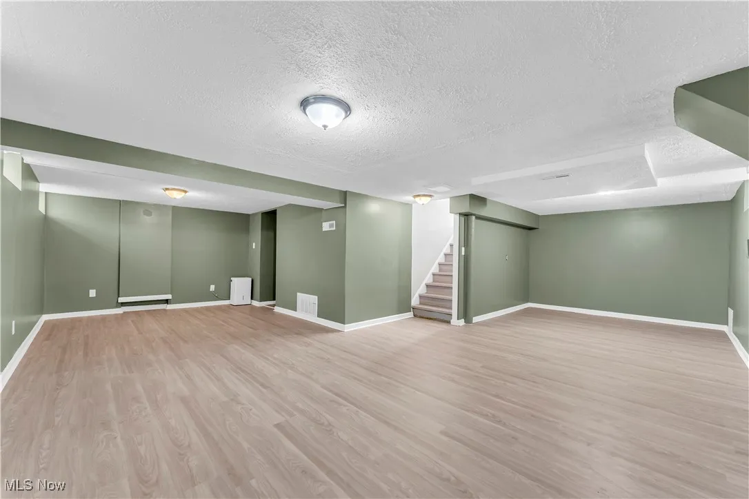 Finished below grade area with a textured ceiling, wood finished floors, and stairs
