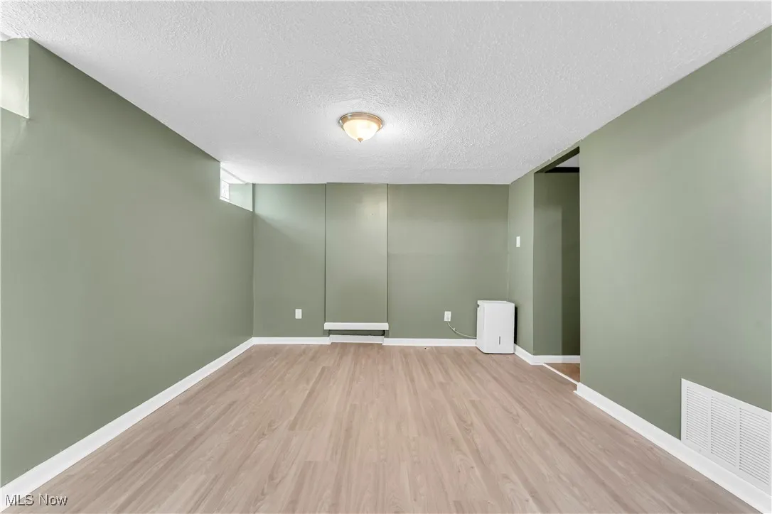 Below grade area with wood finished floors and a textured ceiling