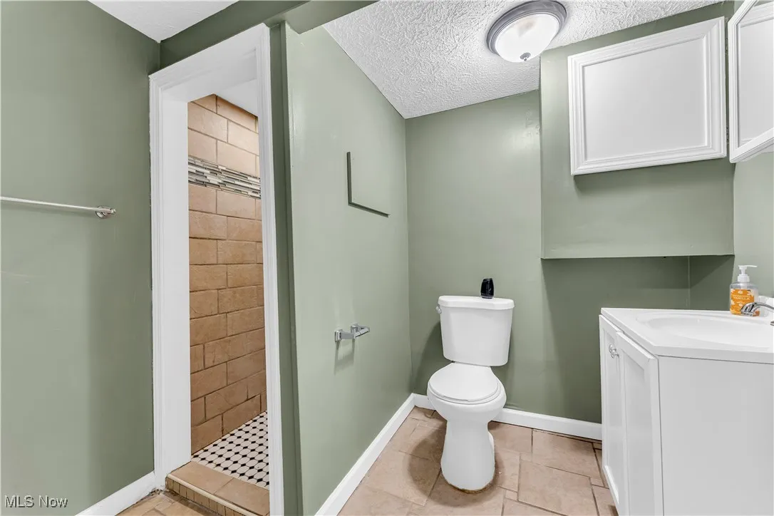 Full bathroom with a textured ceiling, a stall shower, vanity, and tile patterned flooring