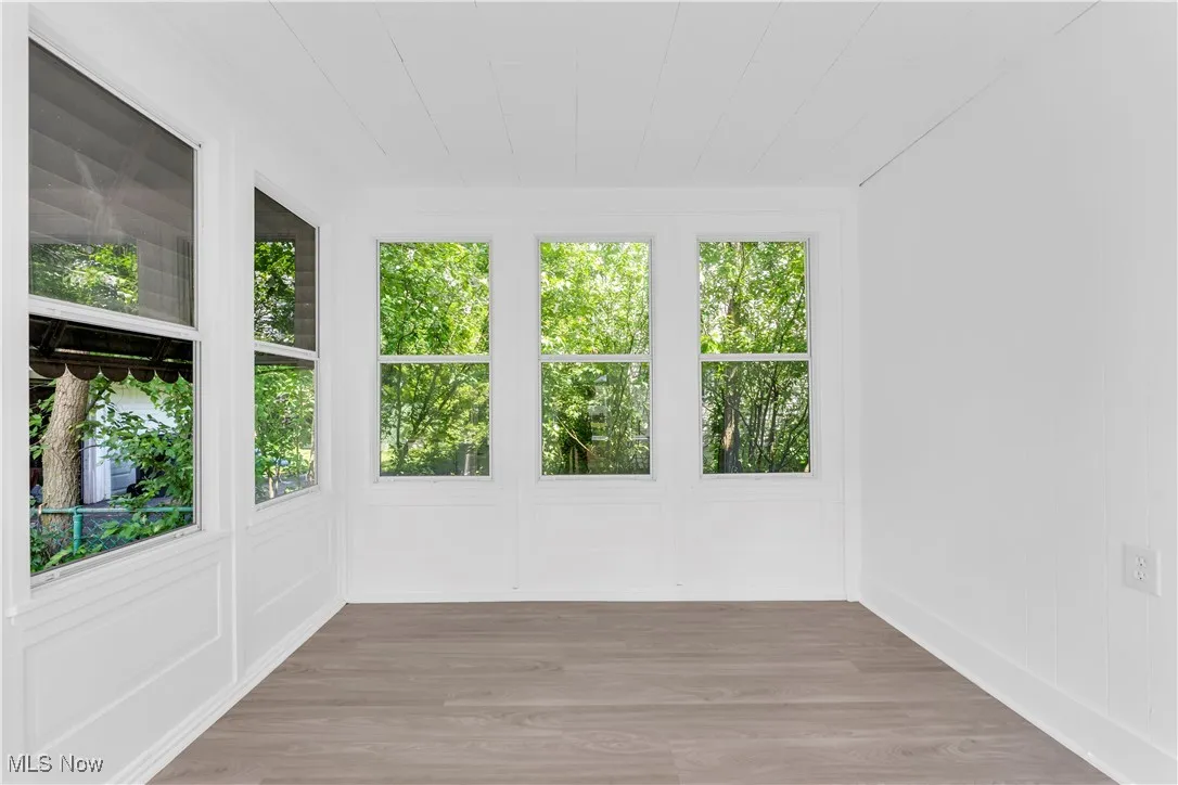 Unfurnished sunroom with wood finished floors and baseboards