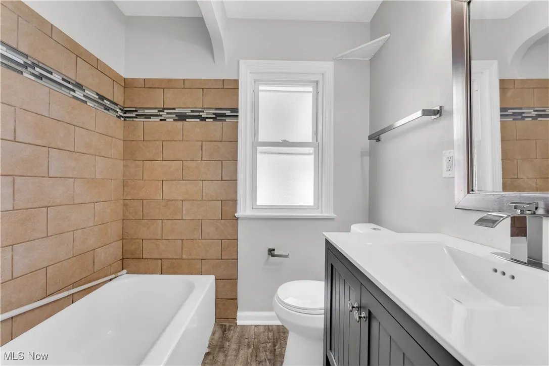 Bathroom featuring vanity, wood finished floors, and tile walls