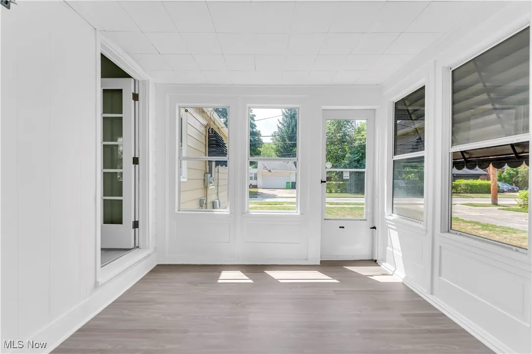 Unfurnished sunroom featuring wood finished floors and a decorative wall