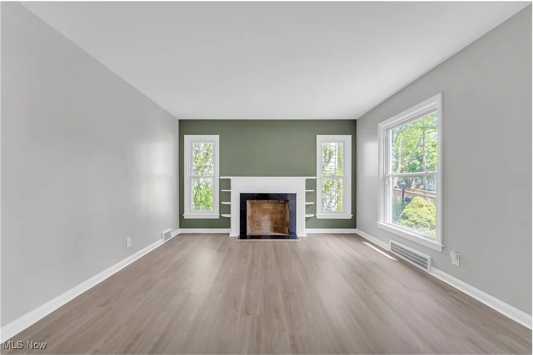 Unfurnished living room with wood finished floors and a fireplace with flush hearth