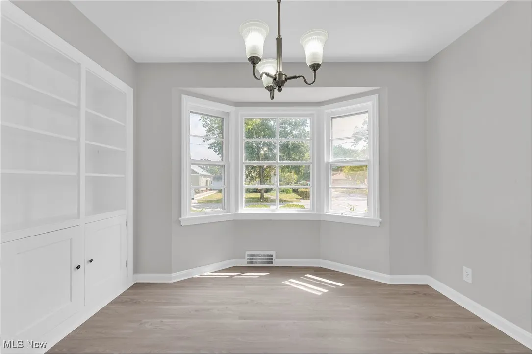 Unfurnished dining area featuring a chandelier and wood finished floors