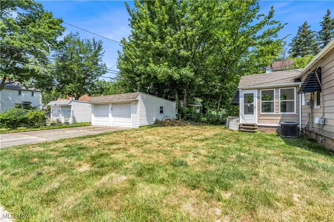 View of grassy yard featuring a garage and an outbuilding