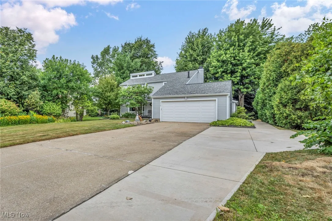 View of front facade featuring concrete driveway, a front yard, a shingled roof, a chimney, and an attached garage
