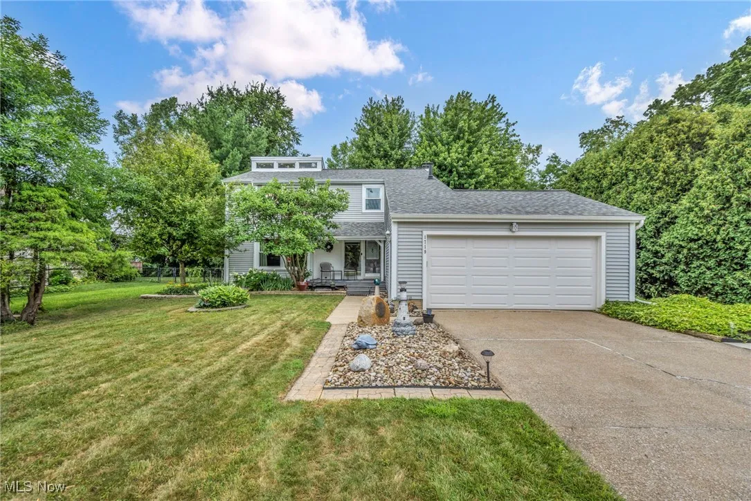 View of front of home featuring driveway, a garage, a front lawn, and roof with shingles
