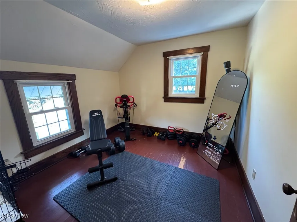 Workout area with hardwood / wood-style floors and vaulted ceiling