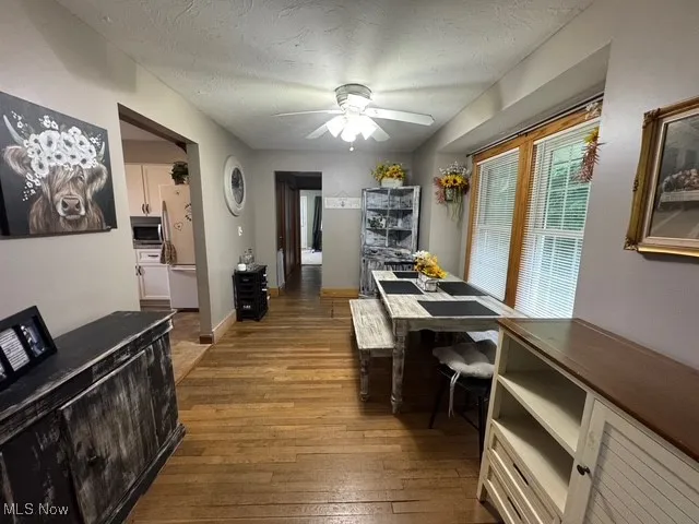 Dining room featuring wood-type flooring, a ceiling fan, and a textured ceiling