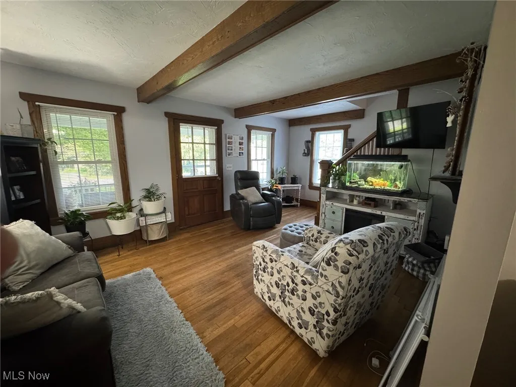 Living room featuring wood finished floors, and beamed ceiling