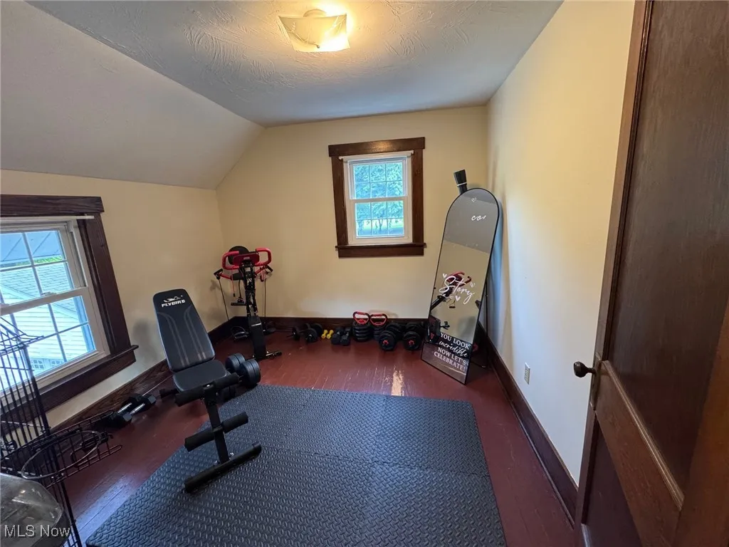 Exercise area with hardwood / wood-style floors, lofted ceiling, could be an office or bedroom