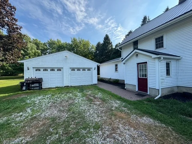 View of home's exterior with a detached garage, an outbuilding, a lawn, and a metal roof