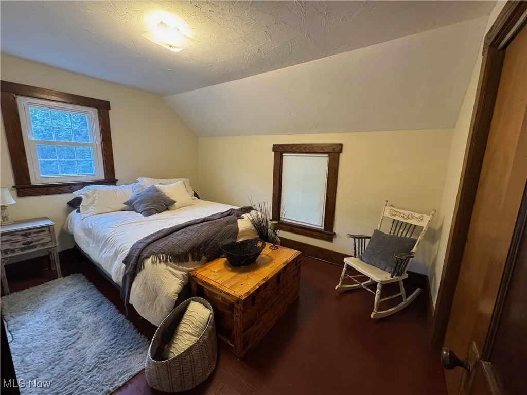 Bedroom featuring vaulted ceiling, wood finished floors, and a textured ceiling