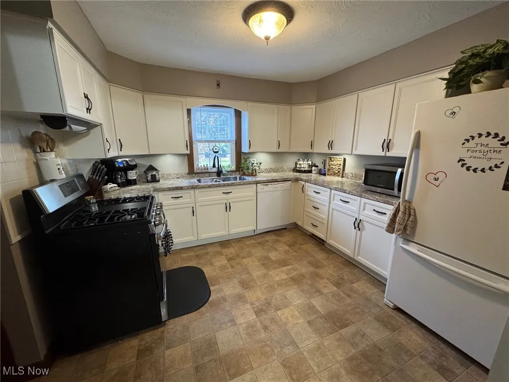 Kitchen featuring appliances, updated white cabinets, counters, and flooring