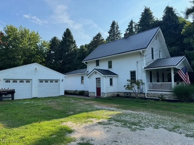 View of side featuring the porch, a garage, and the metal roof