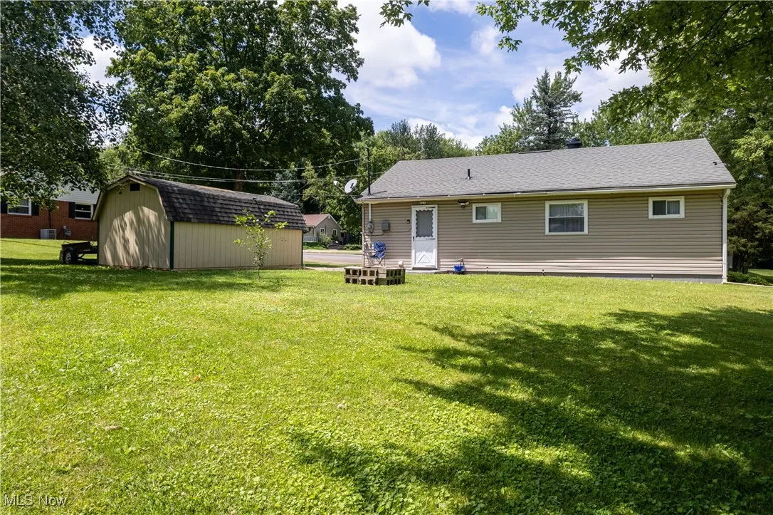 Back of house with a storage shed and a yard