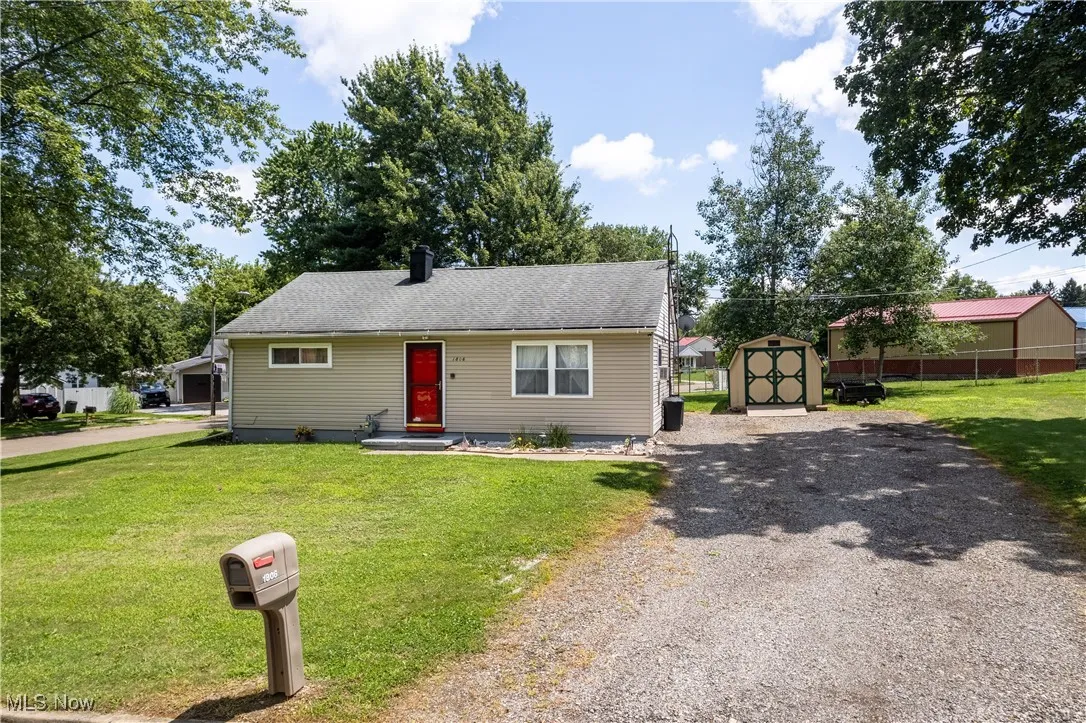 View of front of home with a storage unit and gravel driveway