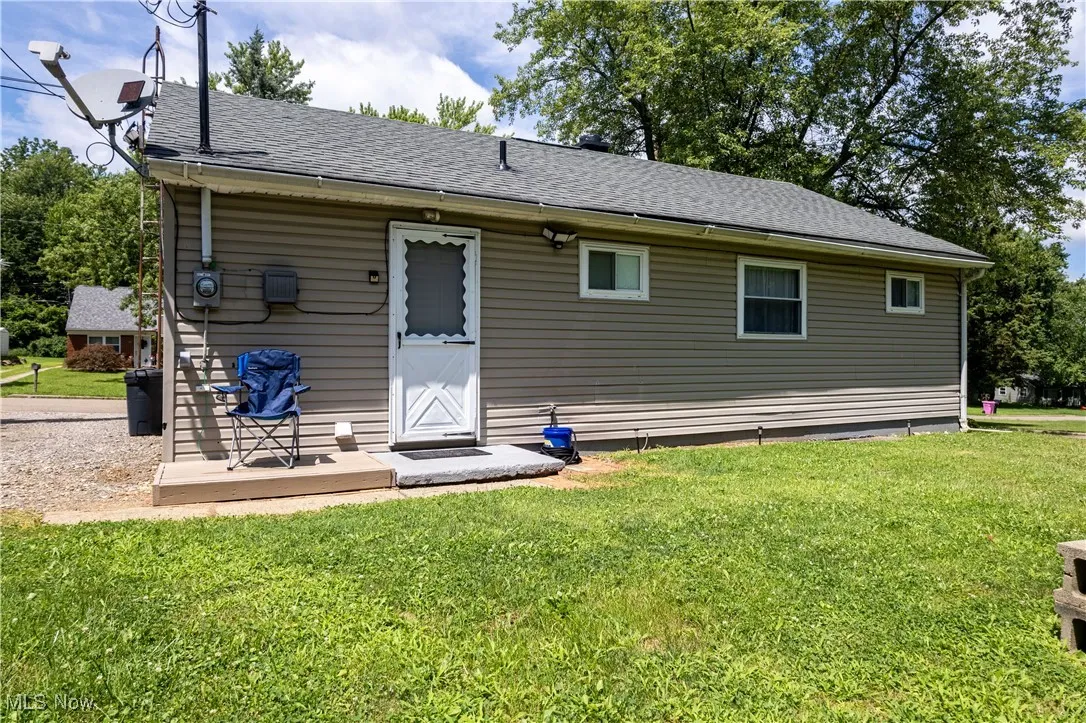 Back of property featuring roof with shingles and a lawn