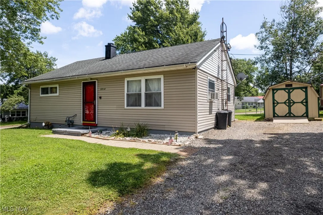 View of front of home featuring a shed, a front lawn, a chimney, and roof with shingles