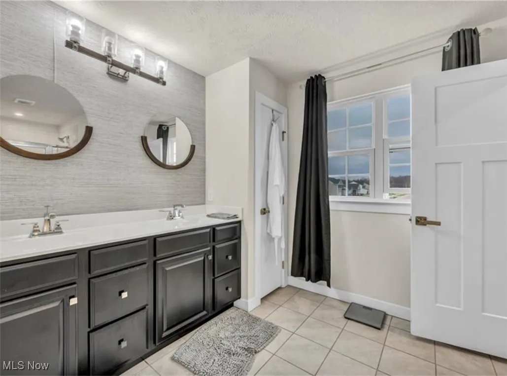 Full bath featuring a textured ceiling, tile patterned floors, and double vanity