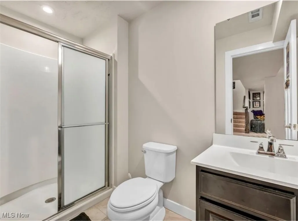 Bathroom featuring vanity, a shower stall, tile patterned floors, and recessed lighting