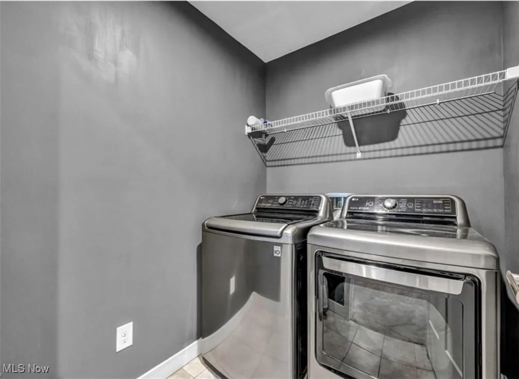 Laundry room with washer and clothes dryer and light tile patterned floors