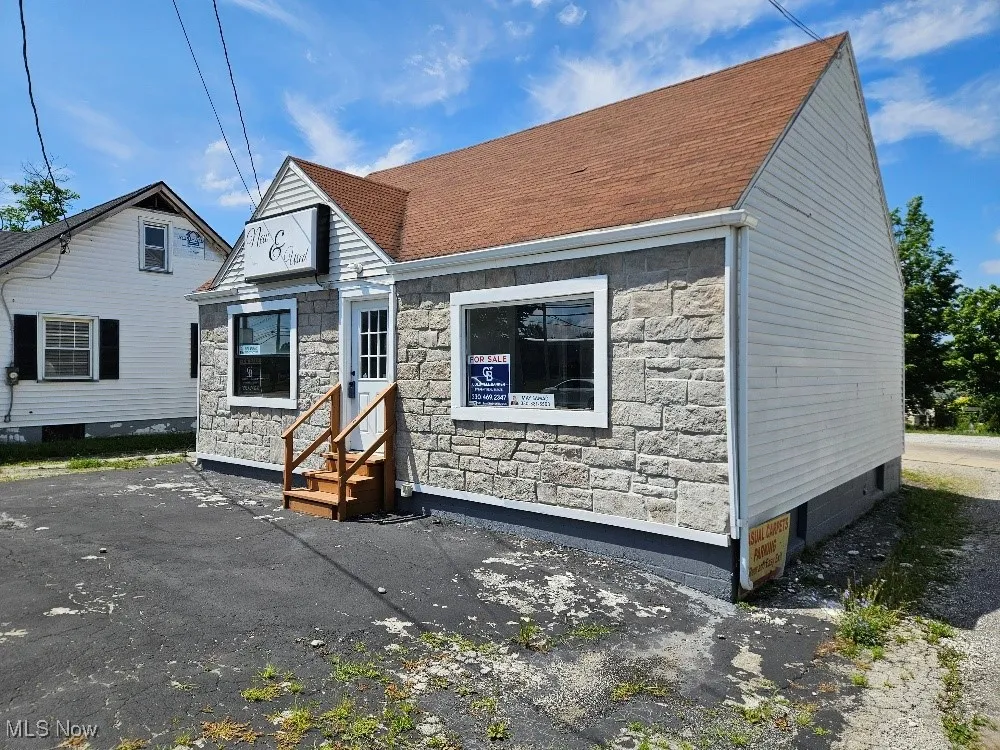 View of front of property with entry steps, stone siding, and a shingled roof