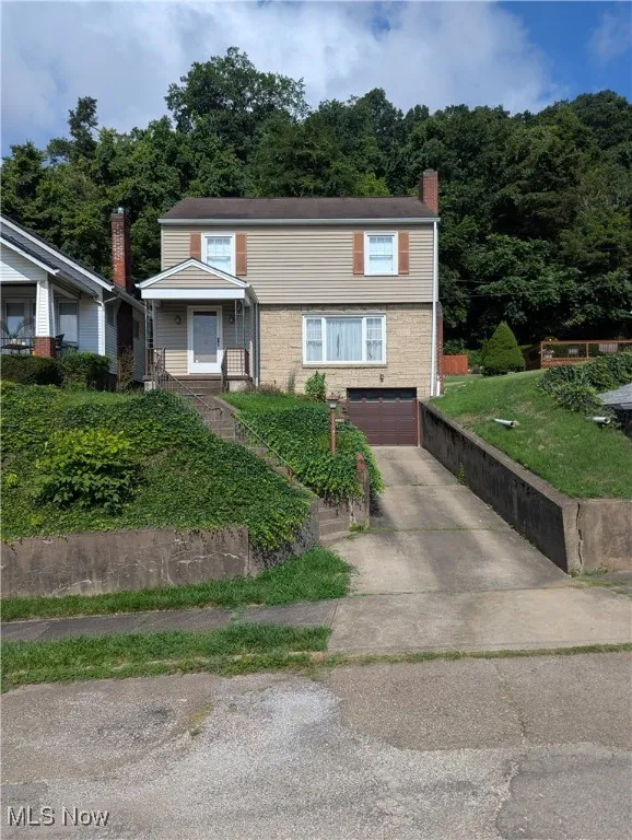 View of front facade with concrete driveway, a garage, and a chimney