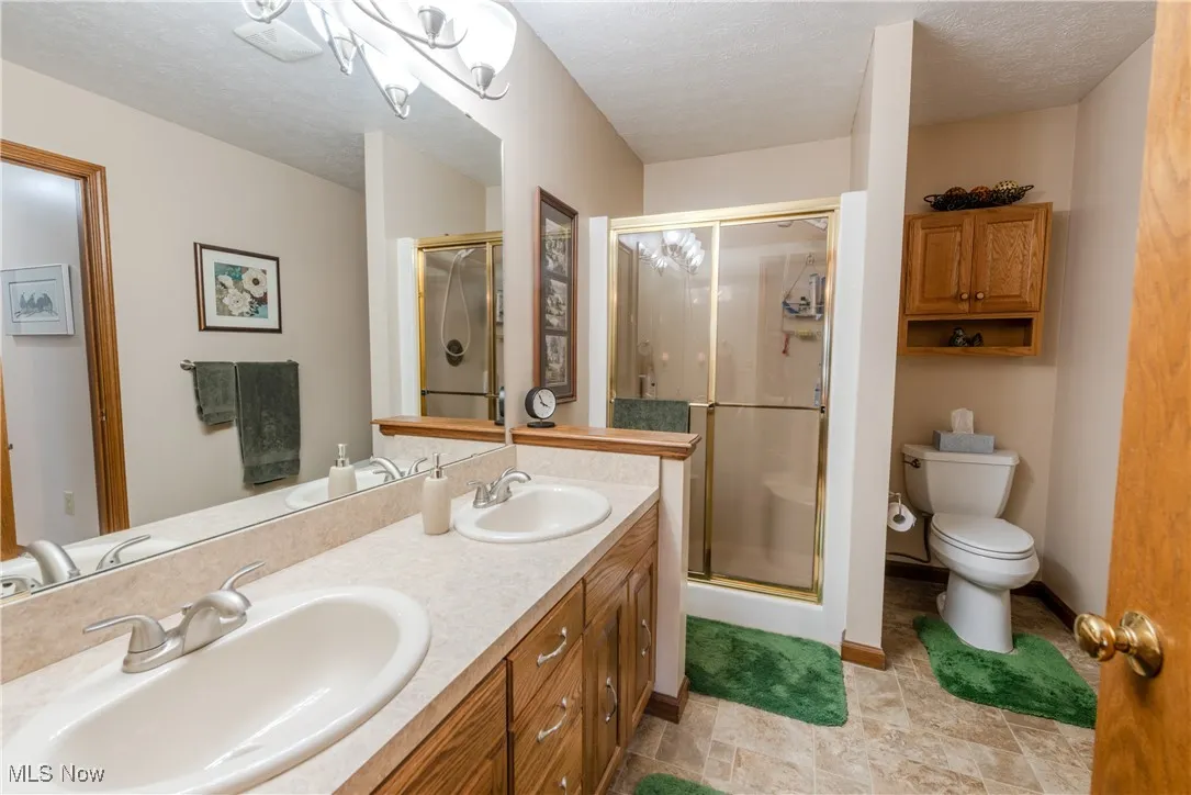 Full bath featuring a stall shower, and double vanity
