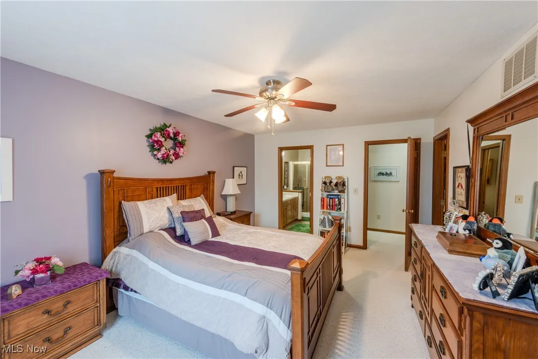 Master Bedroom with light colored carpet, ceiling fan, and ensuite bathroom