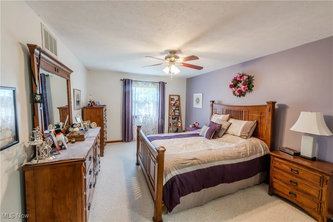 Master Bedroom with light colored carpet, ceiling fan, and ensuite bathroom
