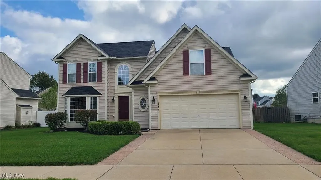 Traditional-style home featuring an attached garage and driveway