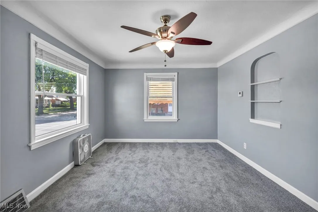 Carpeted spare room featuring plenty of natural light and ceiling fan