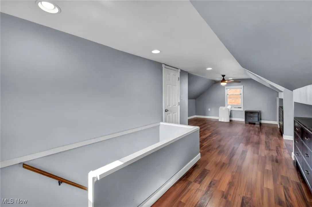 Corridor featuring dark wood-style flooring, recessed lighting, and vaulted ceiling