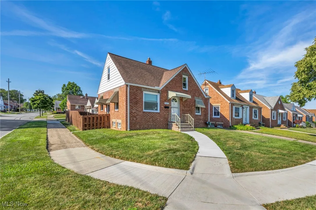 View of front facade featuring a residential view, brick siding, a front lawn, and a chimney