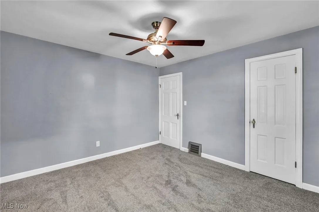 Carpeted spare room with a ceiling fan and baseboards