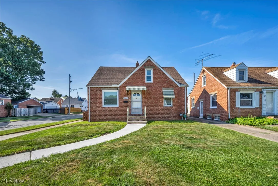 View of front of house with brick siding, a front yard, and a chimney