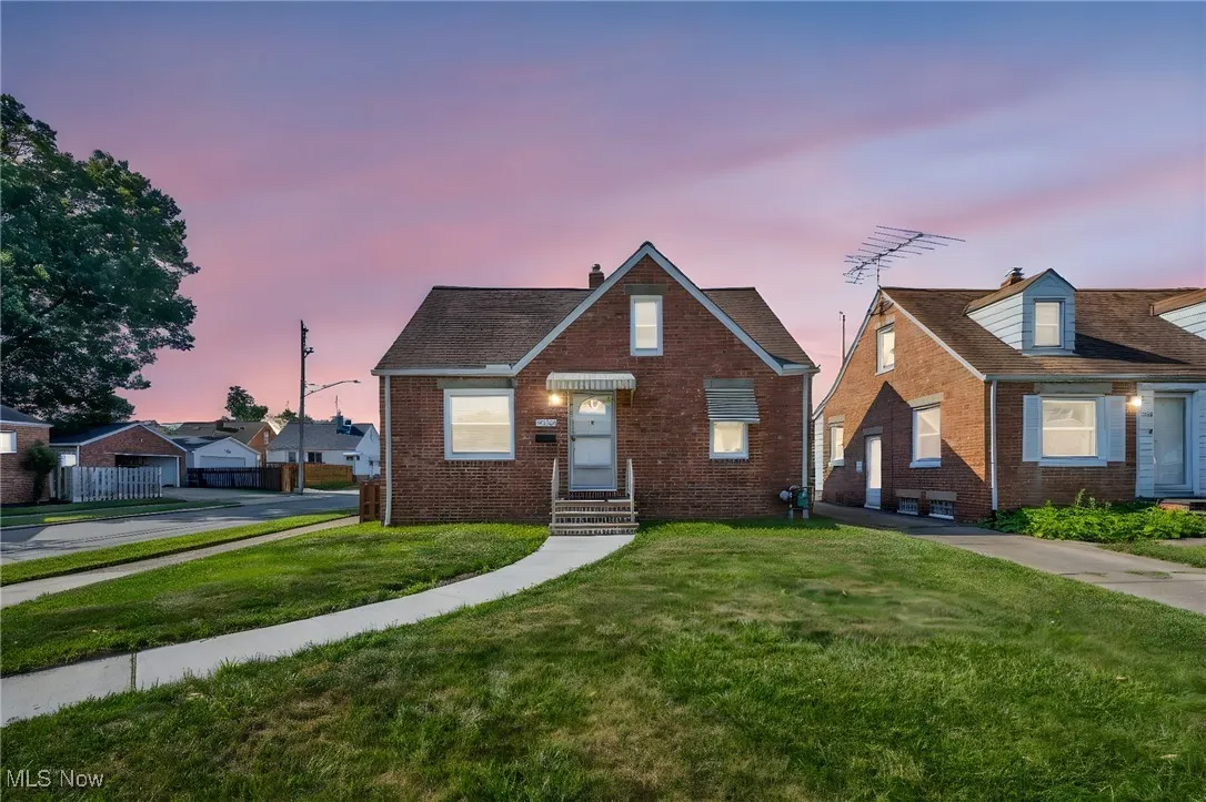 View of front of house with brick siding, a chimney, and a front yard