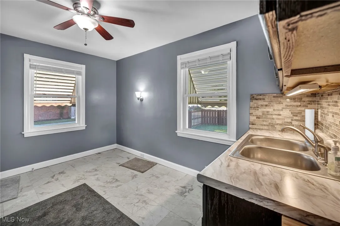 Kitchen with marble finish floors, a ceiling fan, and decorative backsplash