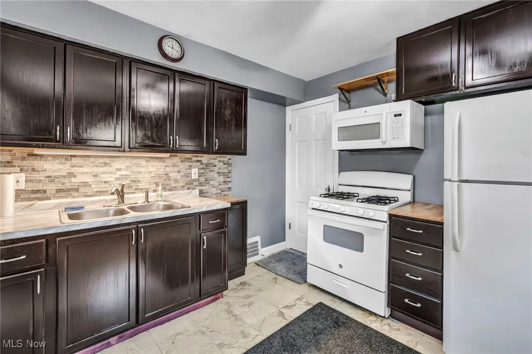 Kitchen featuring white appliances, light countertops, and dark brown cabinets